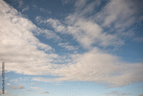 An expansive blue sky is filled with streaks of white and light grey clouds in a dynamic, sweeping pattern, suggesting movement and high altitude.