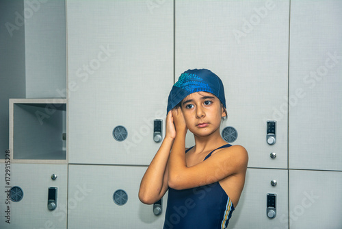 A primary school girl puts on her swimming cap in the locker room as she prepares for swimming