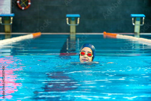 View of a little elementary school girl swimming in a pool