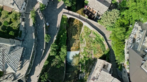 Mostar, Bosnia and Herzegovina Top down aerial drone video of the Crooked Bridge with the Radobolja stream flowing under it toward the Neretva River, near Nezir Agina Mosque in the old town.