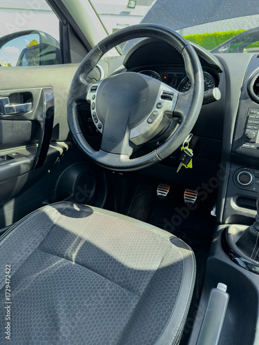 Interior view of a modern vehicle showing the steering wheel and dashboard features on a sunny day