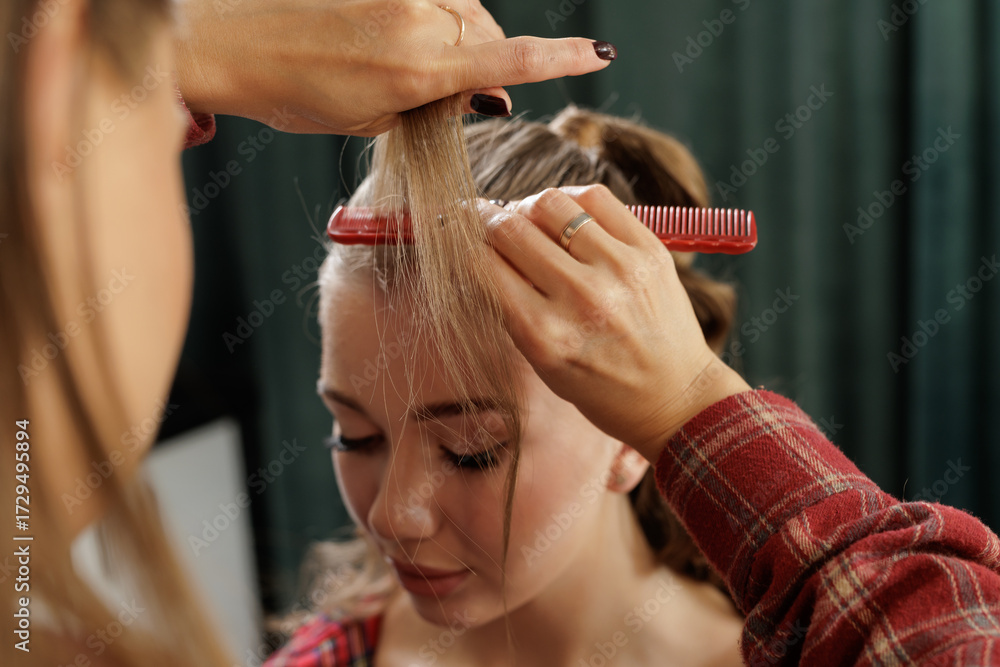 Fototapeta premium Stylist sectioning strands with comb during salon hairstyle prep closeup