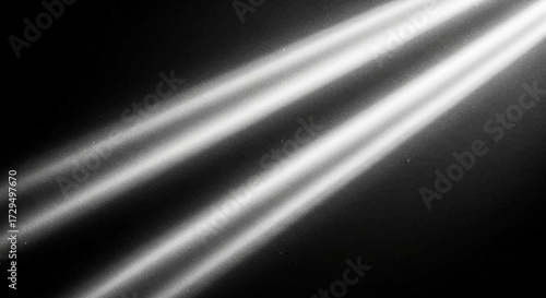 Three bright beams of light shine diagonally across a dark background creating a dramatic and artistic effect