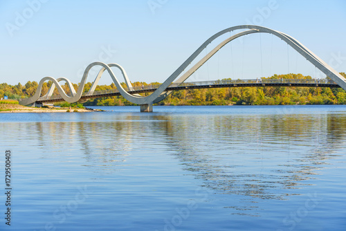Wavy Design Pedestrian Bridge Over Calm Waters in Kyiv with Clear Blue Sky