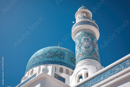 Beautifully decorated mosque minaret with intricate blue tilework and Islamic architecture, standing tall under a vivid, cloudless sky.