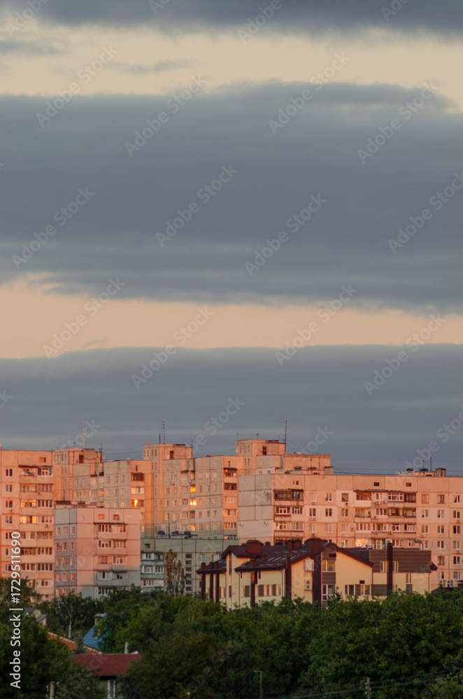 Fototapeta premium Здания на закате освещенные закатным солнцем, тучи