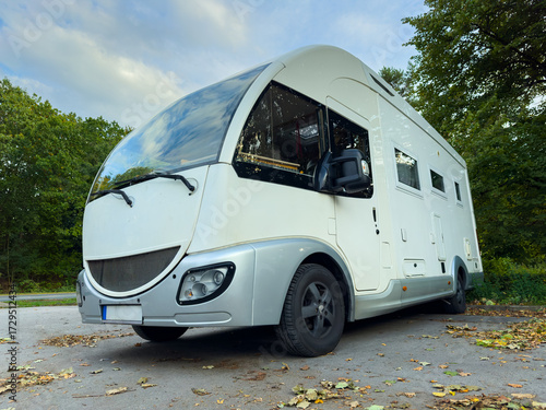 Exploring the great outdoors in a sleek modern camper van, parked in a serene forest setting during the early afternoon