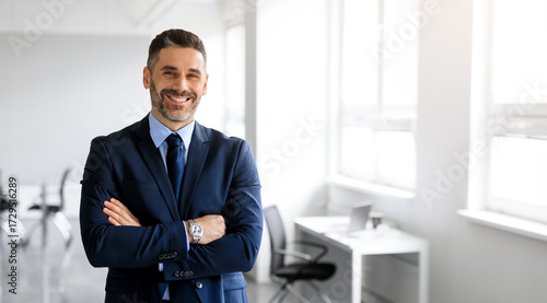 Happy middle aged man in formal outfit manager posing with arms crossed in office interior and smiling at camera, panorama, copy space. Story of success, business, entrepreneurship