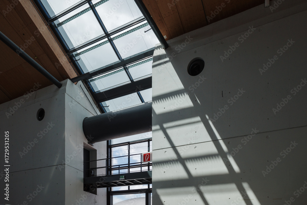 Obraz premium Abstract architectural interior of a modern building with concrete walls and dramatic shadows from a skylight. 