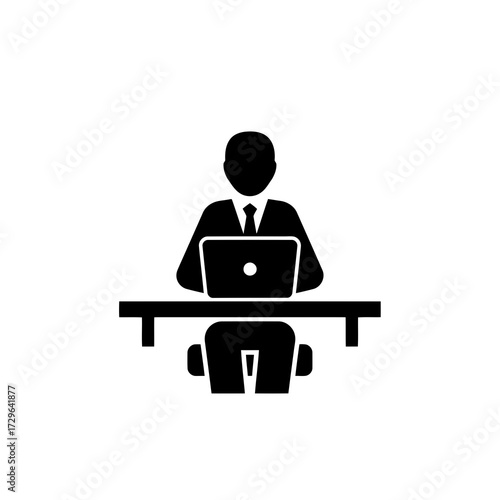 Silhouette of a businessman working on a laptop at a desk