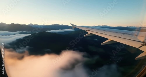 Airplane Wing Overlooking Mountains and Clouds at Dawn