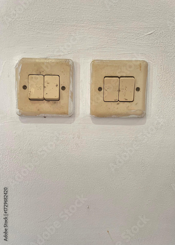Old double light switch on white wall background, vintage electrical power control panel for interior home design