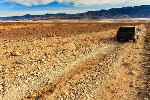 Jeep travels across desert on a rugged dirt road in Death Valley National Park