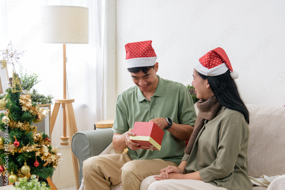 Fototapeta premium Christmas brings happy couple love, joyful winter holiday home celebration, unwrapping christmas gift, creating warm memorable moments indoors for festive season