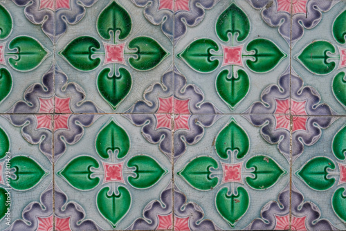 Traditional Peranakan ceramic tiles with floral and geometric motifs in George Town, Penang, Malaysia. The vintage pattern features green, pink, and purple colors, representing decorative design.