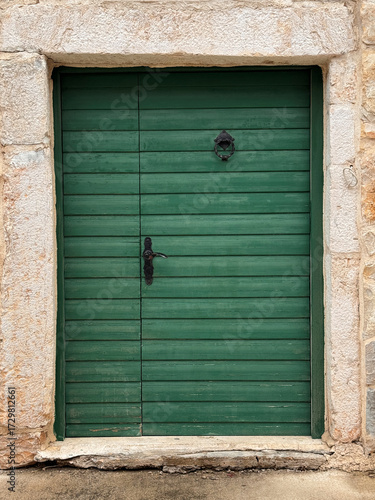 old wooden green door against stone frame on house exterior in Croatia