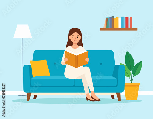 Young woman sitting on a blue sofa reading a book at home, relaxed and focused with cozy interior elements like lamp, shelf, and indoor plant.