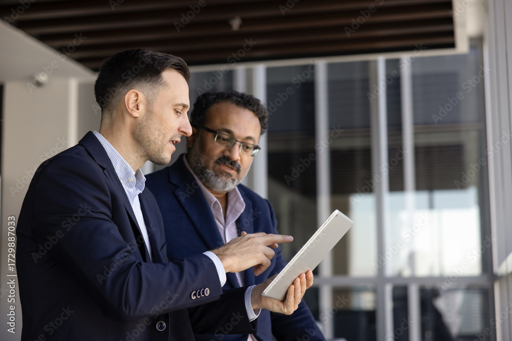 Fototapeta premium Two men colleagues working in office using modern digital tablet