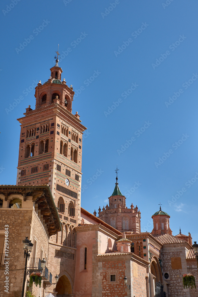 Fototapeta premium Mudejar tower of the Cathedral of Santa Maria de Mediavilla in Teruel with ornamental details and a blue sky in the background