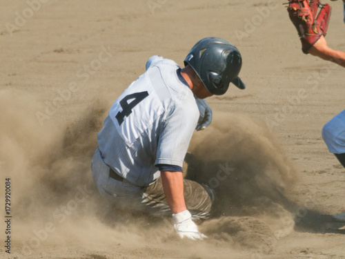 Fototapeta 野球の試合でスライディングした選手と砂ほこり