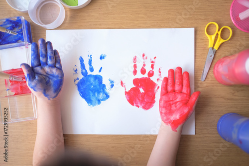 Top view of child handprints with blue and red paint on white paper, sensory play, fine motor skills, creativity, preschool art, fun craft, joyful learning