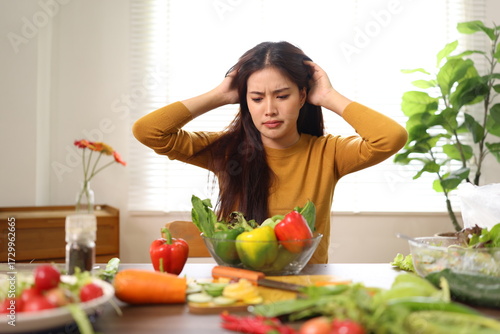 Healthy Eating Headaches Concept. A woman looks stressed with fruits and vegetables on table in room at home.