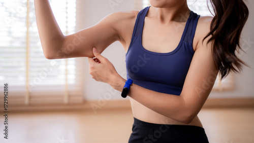 Adult Asian woman pinches arm fat checking body fitness health weight loss progress home gym workout lifestyle