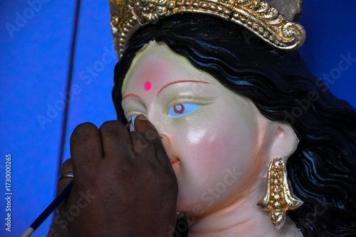 An artiest has been drawing and painting eyes of goddess Durga. Clay idol of Hindu goddess Durga is under preparation.