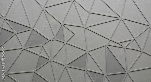 A textured gray surface is adorned with an intricate geometric pattern of interconnected raised lines forming numerous triangles Subtle tonal variations add depth to the abstract design