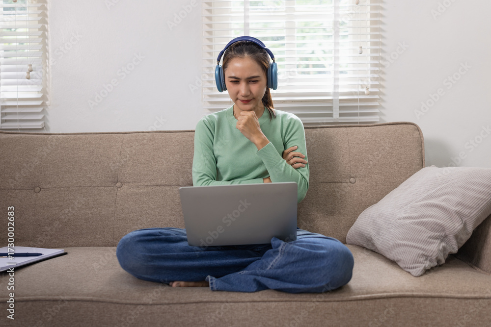 Naklejka premium Woman reading a book with blue headphones and a laptop at home, Relaxation & Leisure Learn online Concept.