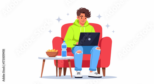A young man in a green hoodie sits in a red armchair, working on a laptop.