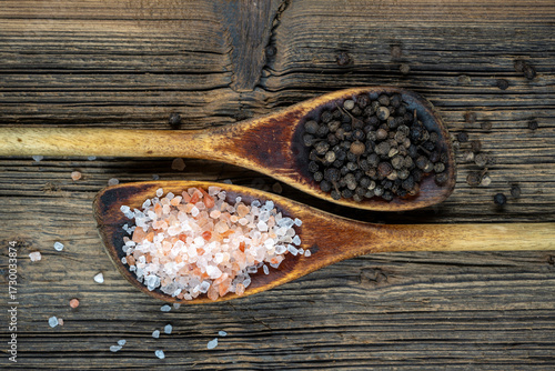 Wooden cooking spoon with coarse salt and black peppercorns