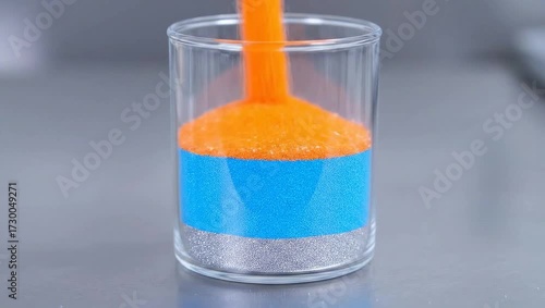 Glistening Silver Micro-Granules Pouring into Clear Glass Beaker, Creating a Foundation in a Detailed Timelapse Shot