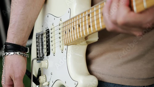Close up of hands playing electric guitar.
