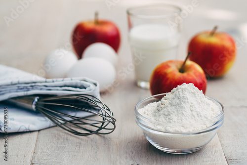 flour, apples and glass of milk on table