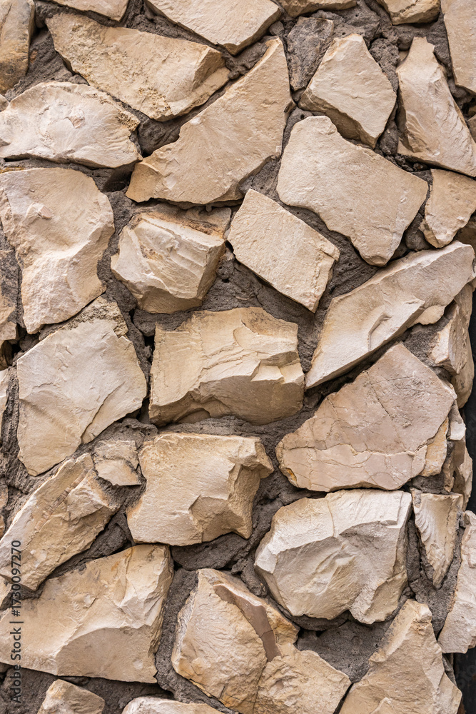 Fototapeta premium Decorative abstract background of a stone wall made of numerous small stones of different shapes. stone vertical background. natural stone texture.