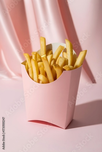 golden french fries in a light pink paper french fry container against a soft pink background