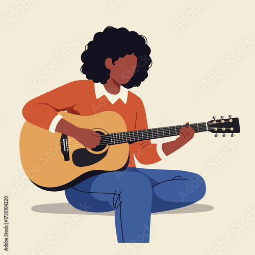 Person playing acoustic guitar, cross-legged on floor