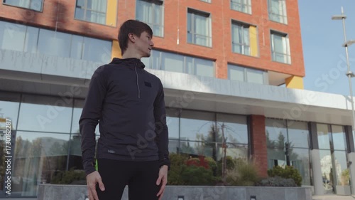 A fit man uses his smartwatch to prepare for an urban workout, blending tech with exercise.