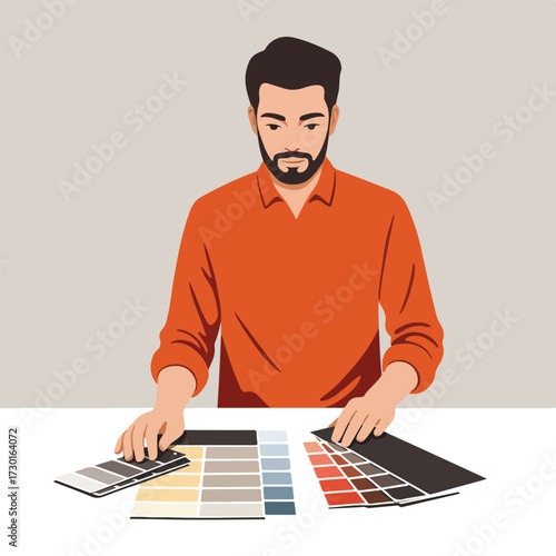 Man selecting colors, holds swatches, wearing orange shirt, at a white table