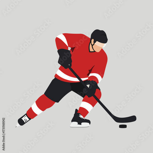 Hockey player in red jersey skating with puck against a grey background