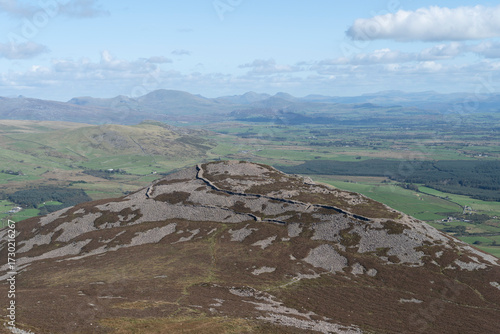 'Town of the Giants,' Tre'r Ceiri, iron age hill fort on the Yr Eifl mountain range, Gwynedd Wales UK, with views to Snowdonia in the distance under a blue sky with cloud