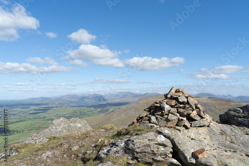 Summit cairn on Gyrn Goch mountain, Gwynedd, Wales, UK, with views towards Snowdonia under a blue sky with cloud.