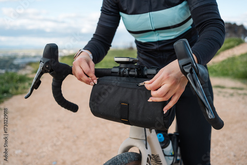 Cyclist adjusting handlebar bag on gravel bike during scenic ride