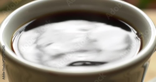 Close-up of swirling coffee in a white cup outdoors