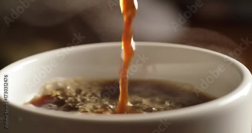Coffee being poured into a steaming white cup