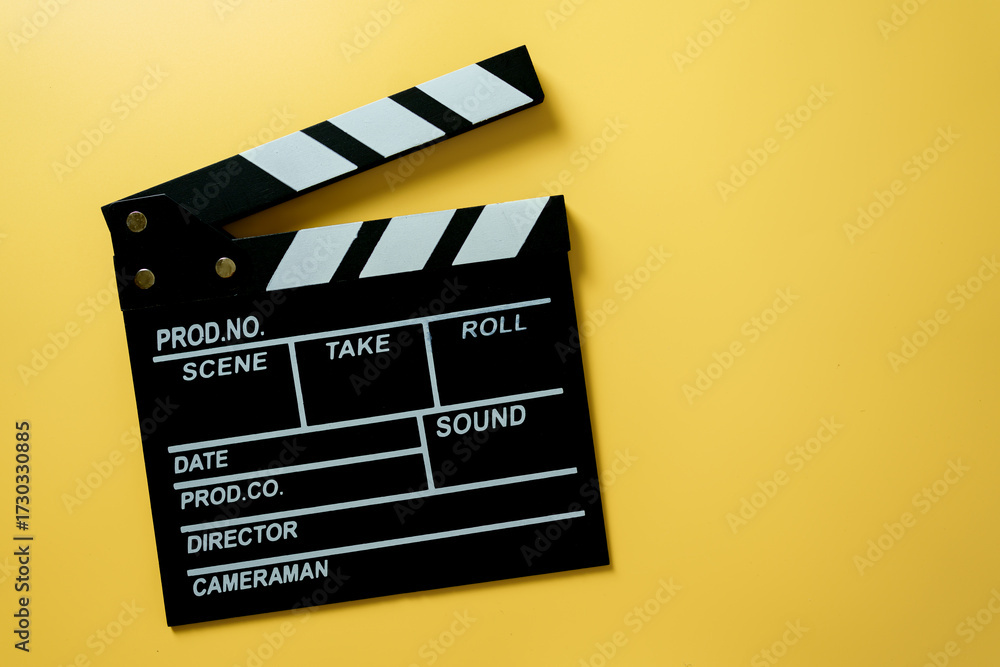 Naklejka premium Black movie clapperboard on yellow background, concept of film production, cinema industry, video content creation, and creative media.