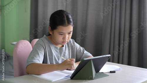 asian child student write learning on computer tablet screen by touch pen or kid girl studying writing art drawing on study online class by pad or young person learn from home school by technology
