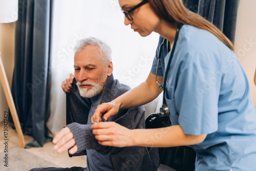 Fotografi Nurse assisting senior man dressing home care
