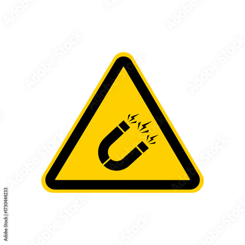 Warning sign depicts strong magnetic field hazard in yellow triangle, indicating potential danger and caution in industrial setting.